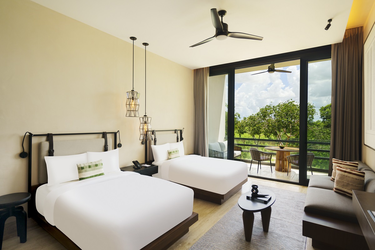 Bright room with two beds and patio at Hacienda Xcanatun, Angsana Heritage Collection, overlooking greenery.